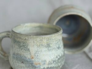 Two handmade ceramic mugs on a linen background